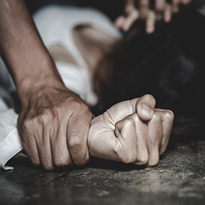 Close-up of a man's fist clenching a woman's wrist, representing assault and legal help
